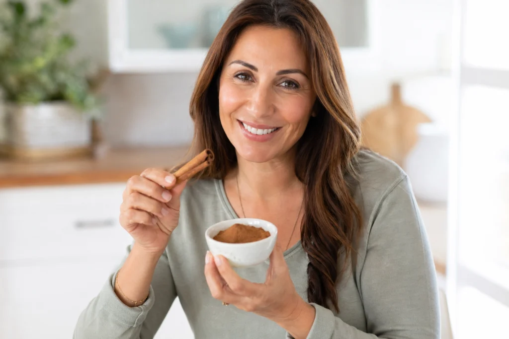 Woman holding cinnamon sticks and ground cinnamon — natural blood sugar support with cinnamon