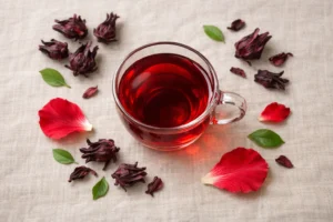 Hibiscus tea in a glass cup surrounded by dried hibiscus calyxes for psoriasis and eczema relief
